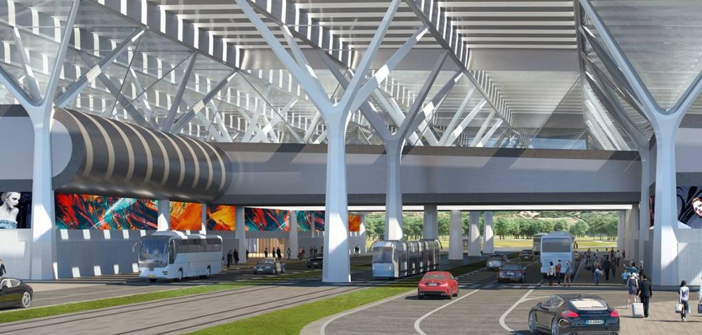 Renderização de um terminal de transporte moderno com teto de vidro e pilares brancos em forma de árvore. Abaixo, uma passarela elevada com painéis coloridos e um túnel cinza. No nível do solo, ônibus, carros e um trem circulam em vias separadas, enquanto pedestres caminham em calçadas. Ao fundo, árvores verdes.