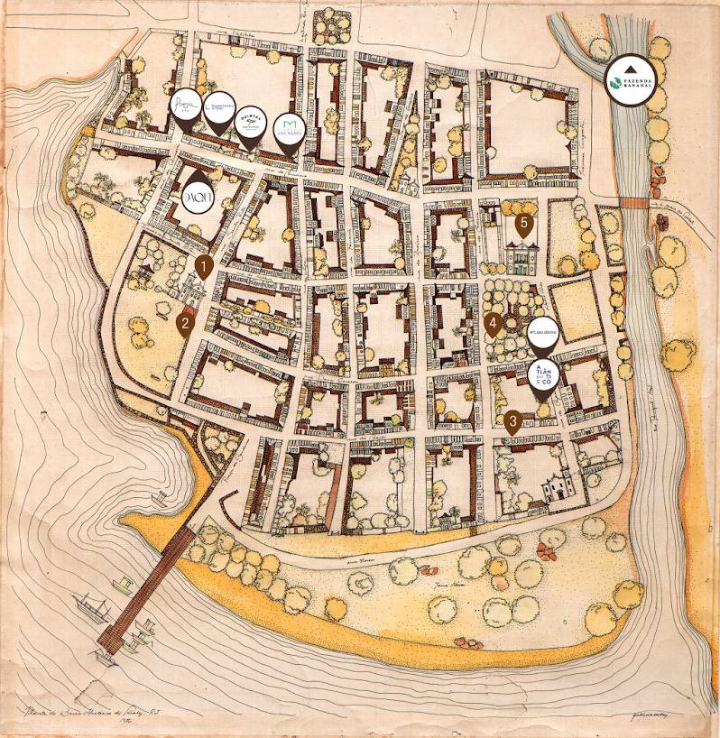 Mapa antigo em tons sépia e marrons, mostrando um assentamento urbano com ruas, edifícios e áreas verdes. Há um rio à direita, um cais com barcos à esquerda e marcadores de localização com logotipos de empresas e números, indicando pontos de interesse