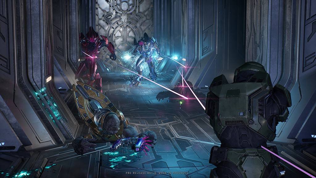 Cena de jogo com três personagens futuristas em combate. Um soldado verde está de costas, atirando raios roxos em dois inimigos: um vermelho e outro azul, ambos com armaduras brilhantes. Um terceiro inimigo, de armadura dourada, está caído no chão, com uma arma roxa ao lado. O cenário é uma estrutura metálica escura com detalhes luminosos azuis