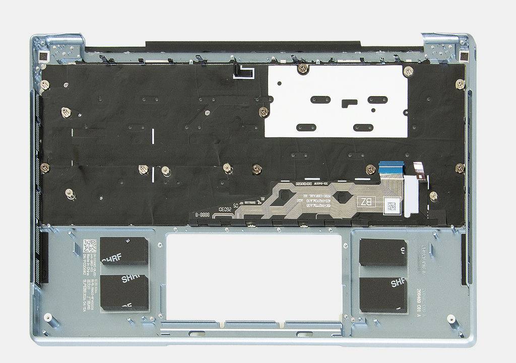Vista superior do interior de um notebook, mostrando a parte traseira do teclado e do touchpad, com circuitos e parafusos visíveis